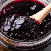 Blueberry jam in a mason jar with wooden spoon.