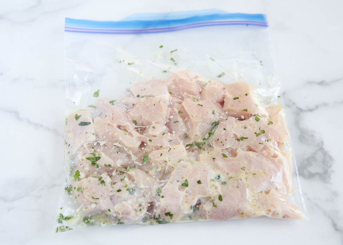 Chicken marinating in a plastic bag.