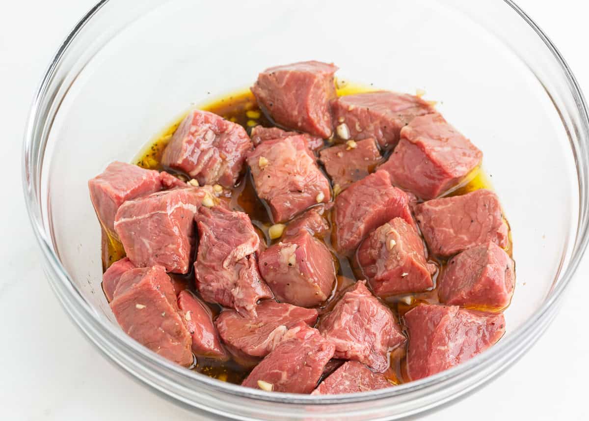 Steak cubed in a bowl with marinade.