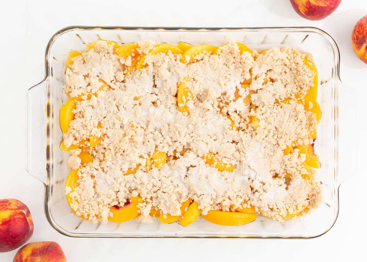 Peaches in baking dish with unbaked cobbler topping.