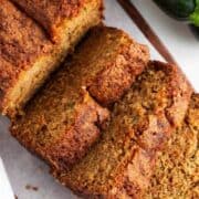 A loaf of zucchini bread with three pieces sliced.