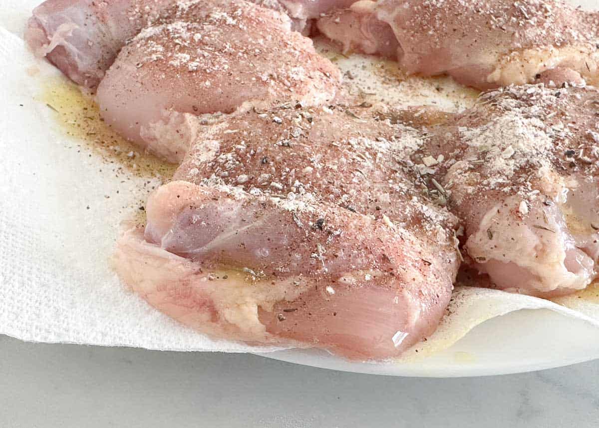 Raw chicken thighs with seasoning.