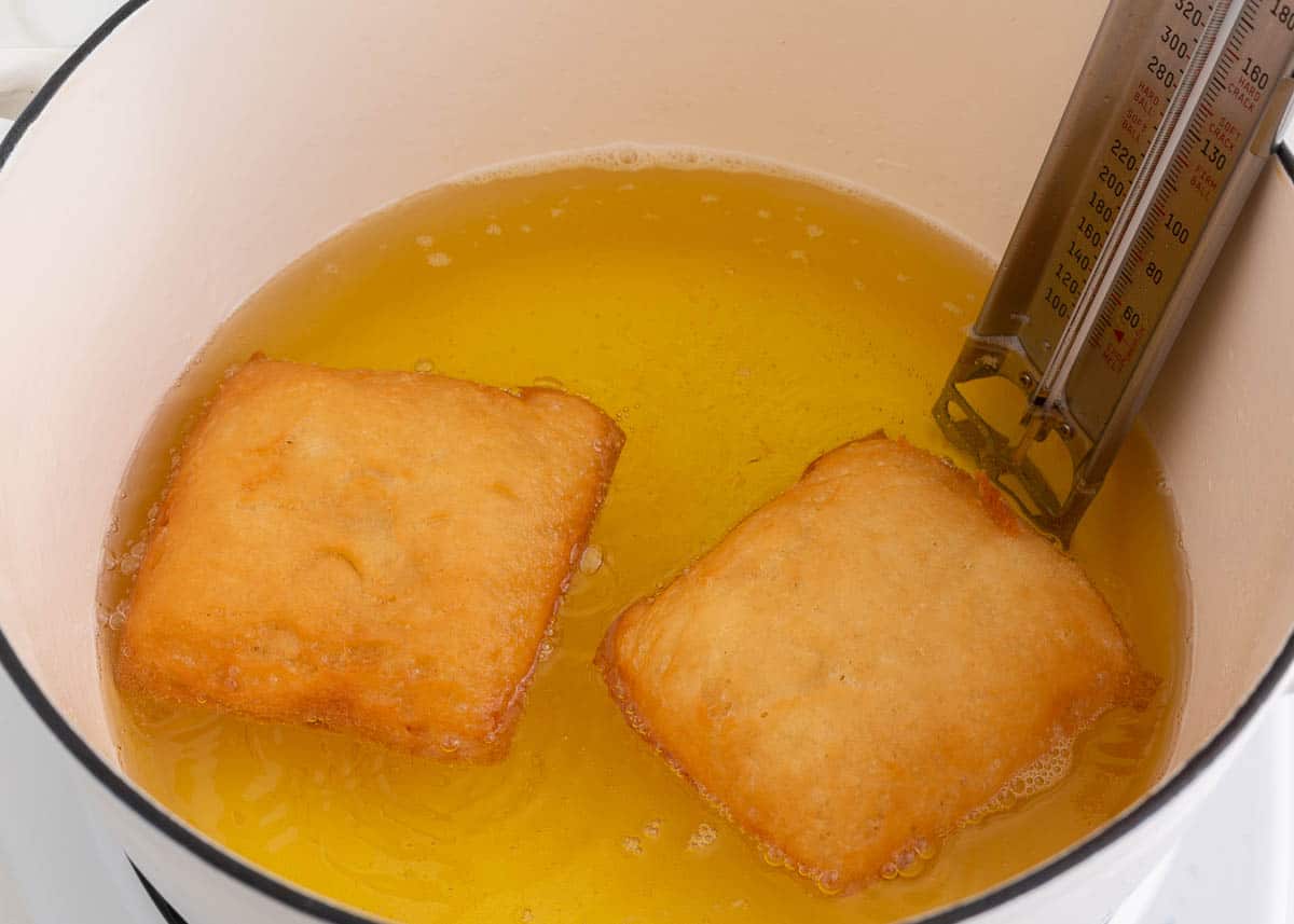 Frying beignets in a pot of hot oil.