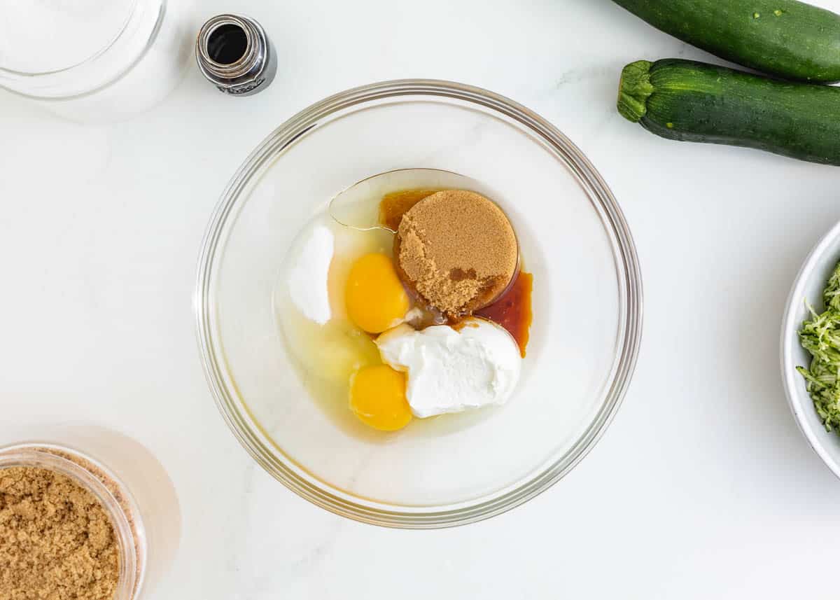 Eggs, sugar, sour cream, brown sugar and oil in a bowl.