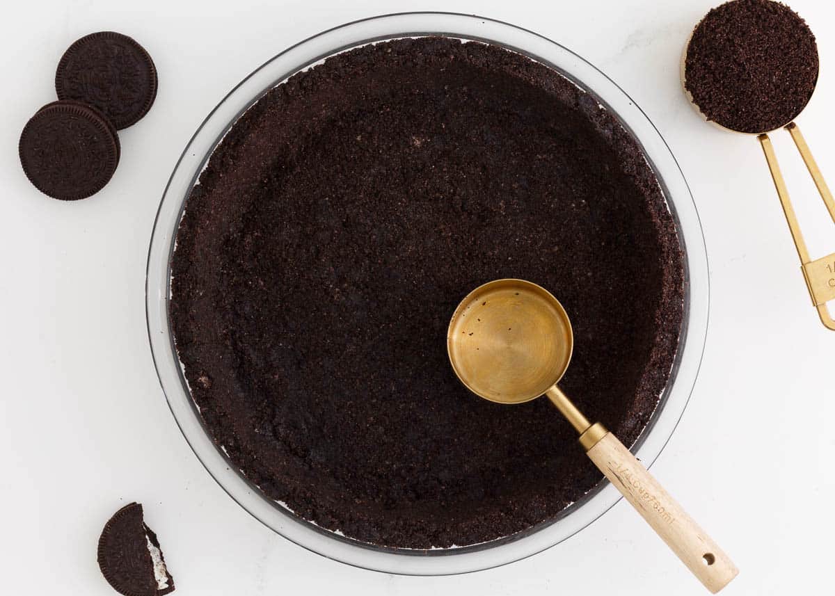 Pressing an Oreo crust into a pie dish.