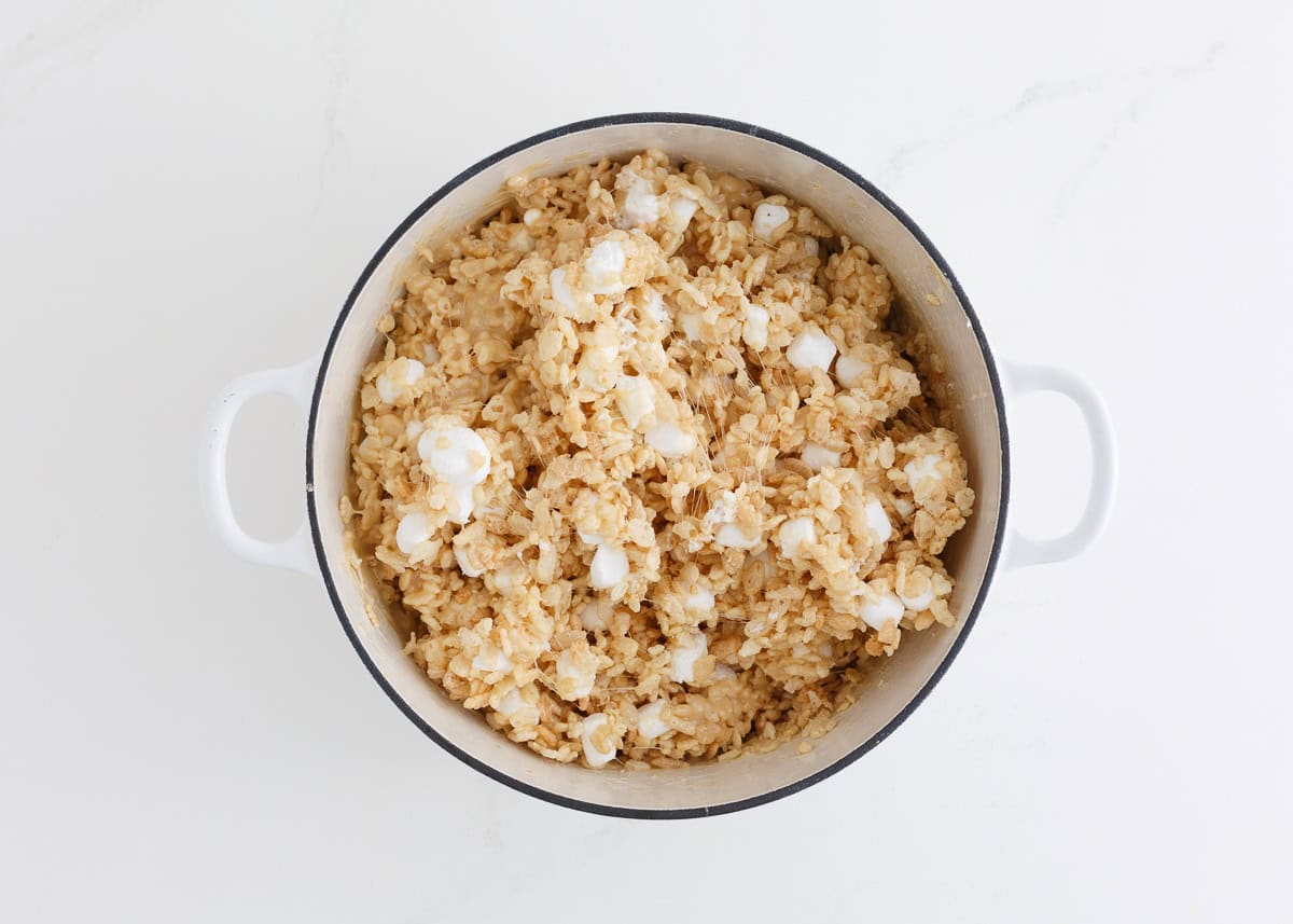 Adding cereal and more marshmallows to a pot.