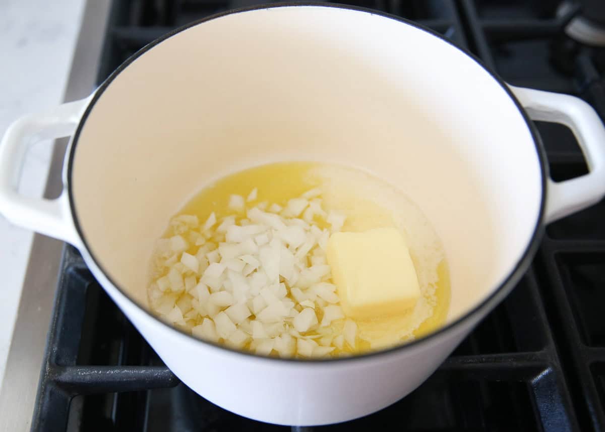 Butter and onion sauteing in a pot on the stove.