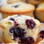 A unwrapped blueberry muffin with a bite missing.