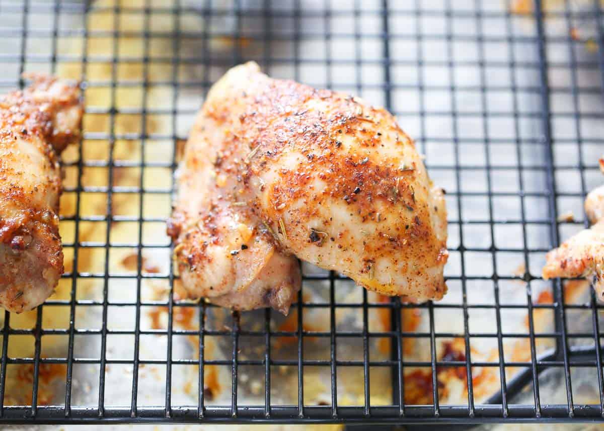 Chicken thighs on baking rack set on a baking sheet.