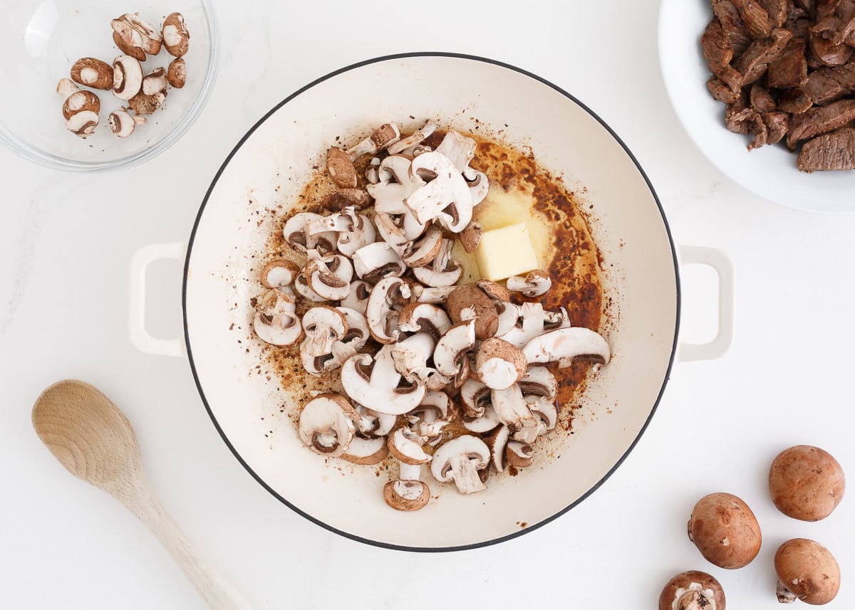 Mushrooms and butter sauteing in a skillet.