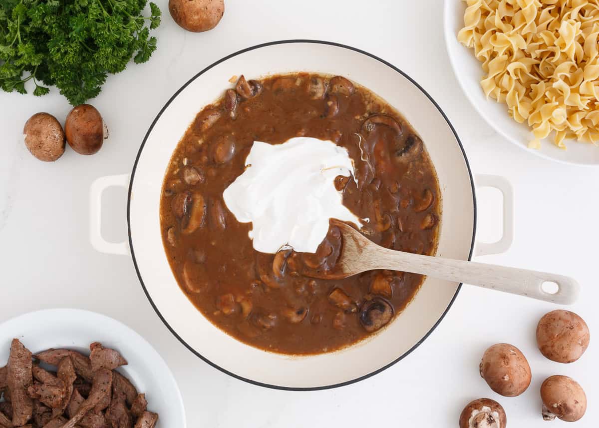 Stroganoff sauce with sour cream being stirred into it.