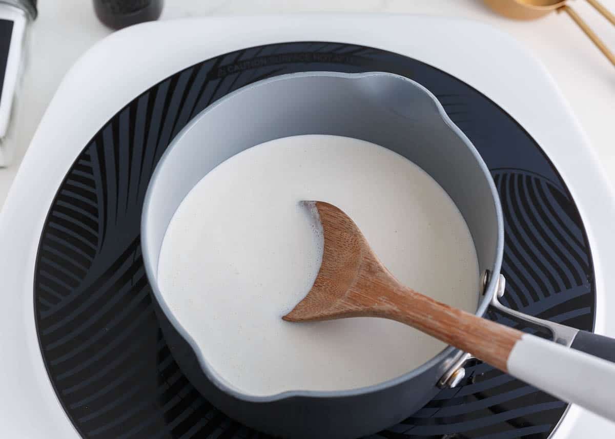 Heating cream in a pot on the stove.