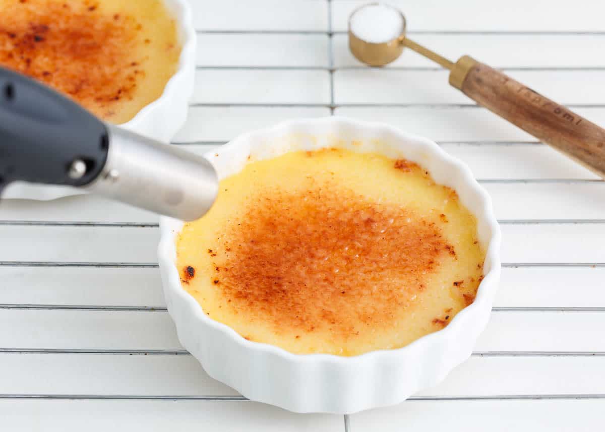 Using a torch to caramelize the sugar topping on creme brulee.