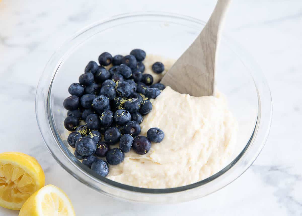 Blueberries and lemon zest in a bowl of muffin batter.