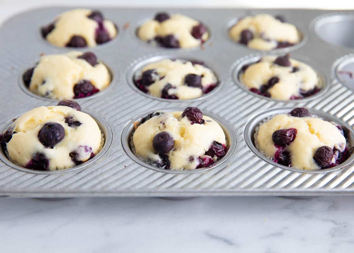 Baked lemon blueberry muffins in a muffin tin.