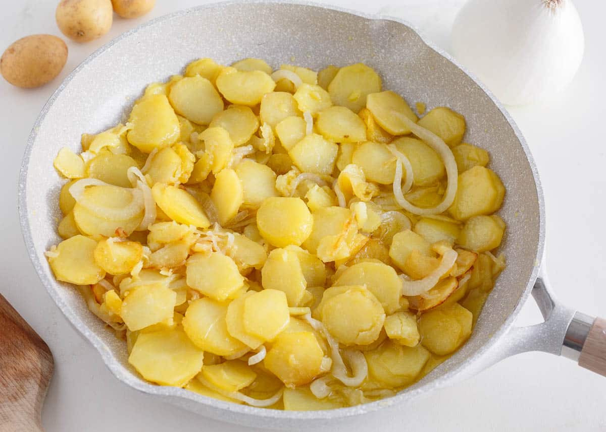 Onions and potatoes in a skillet.