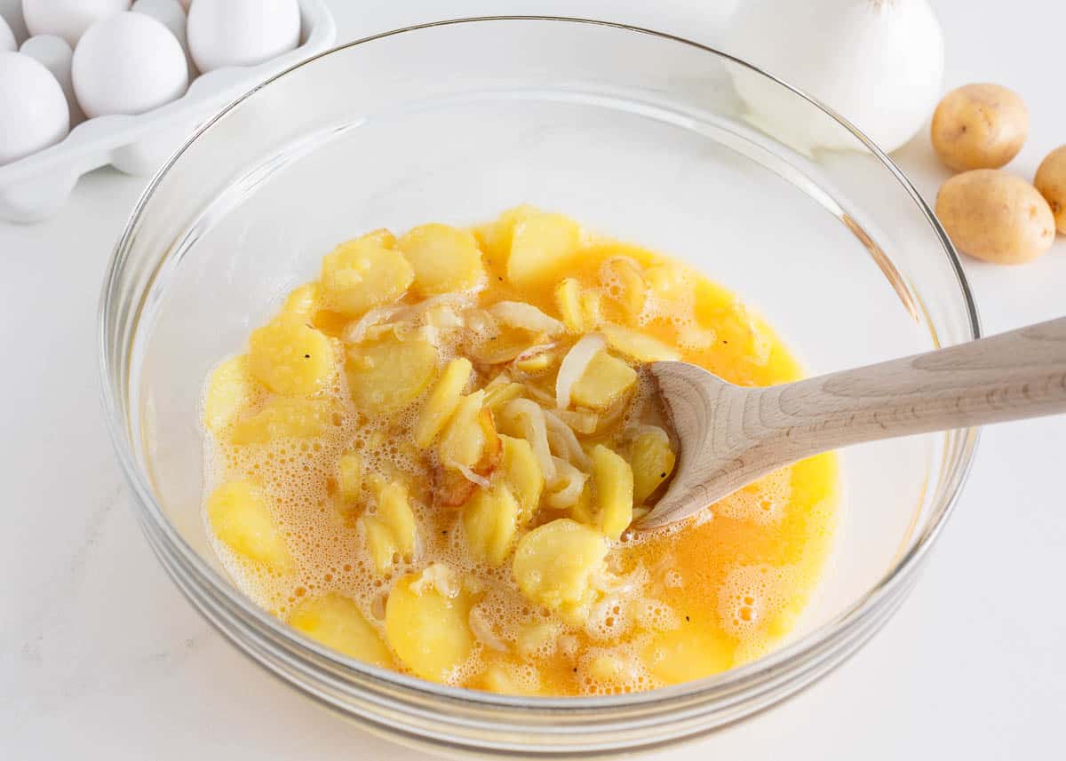 Egg mixture with potatoes and onions in a bowl.