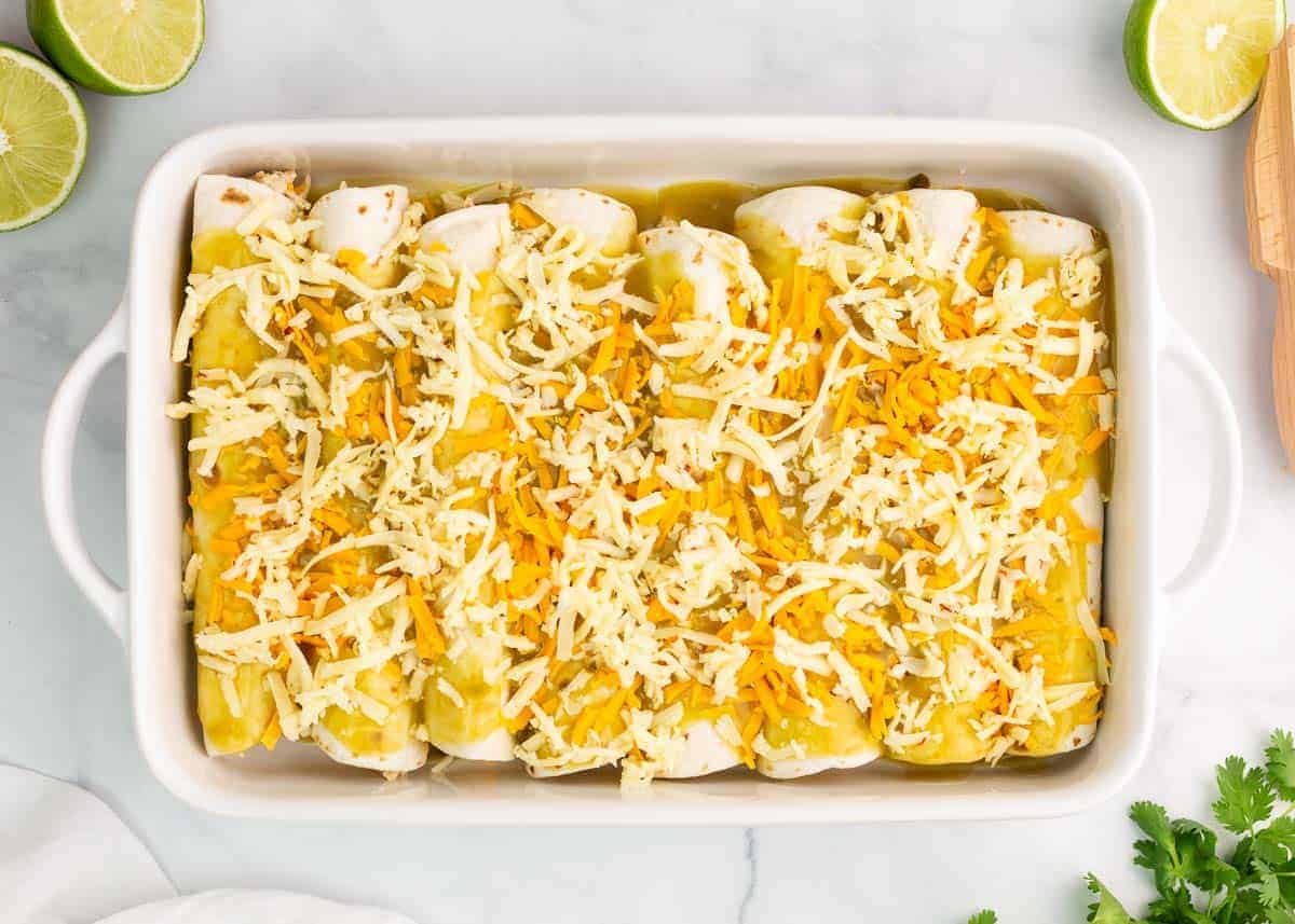 Green chile chicken enchiladas in a white baking dish.