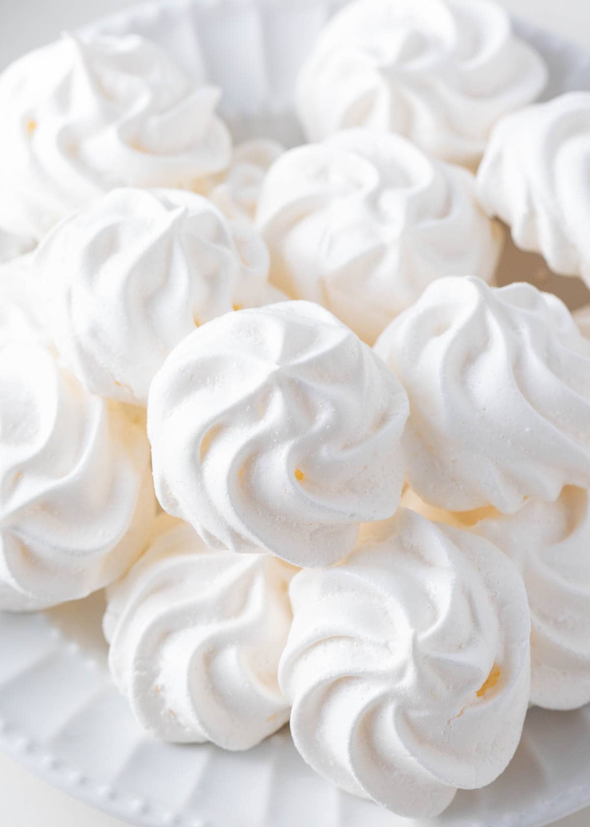 Vanilla meringue cookies on a white plate.