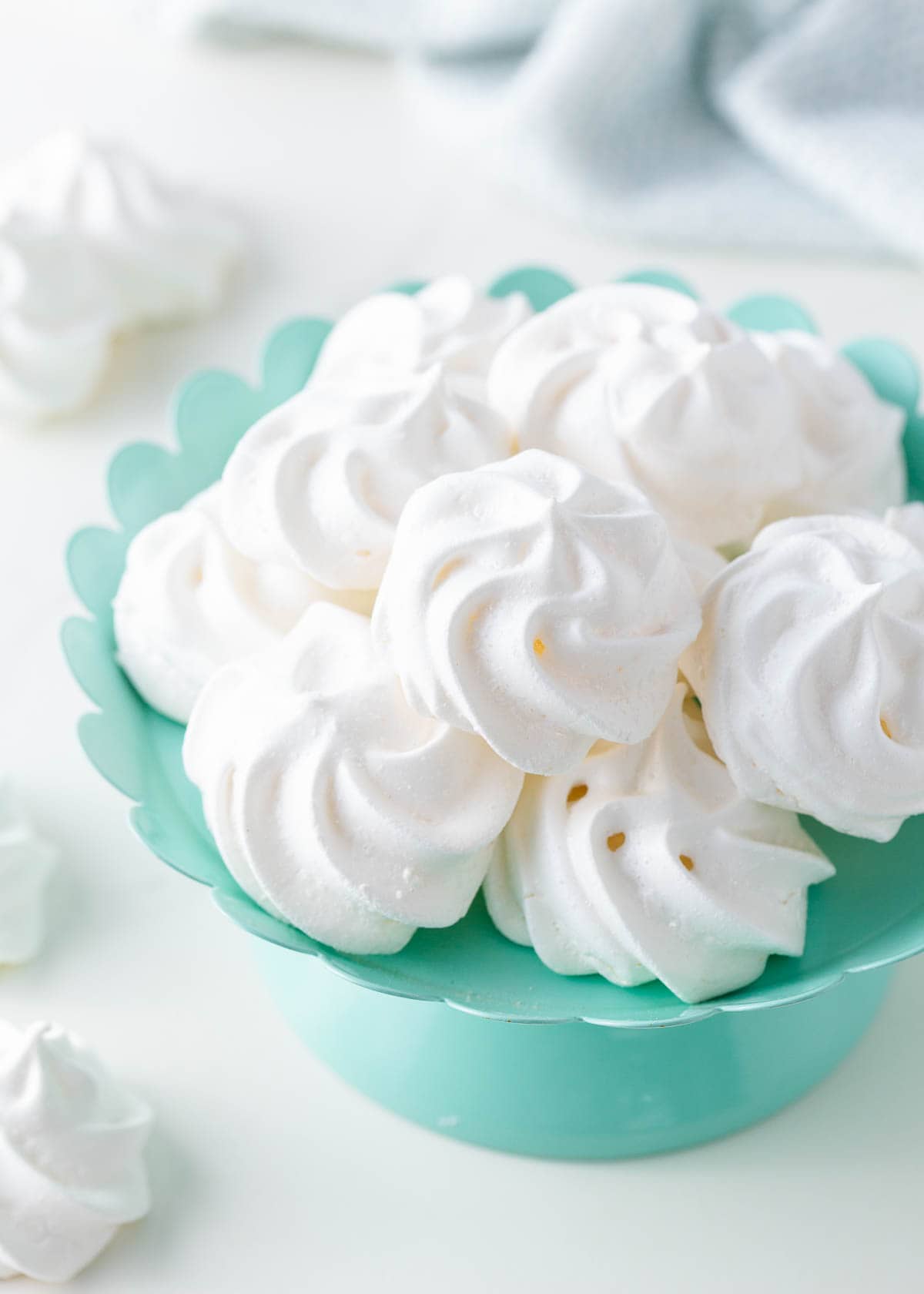 Meringue cookies in a colored bowl on the counter.