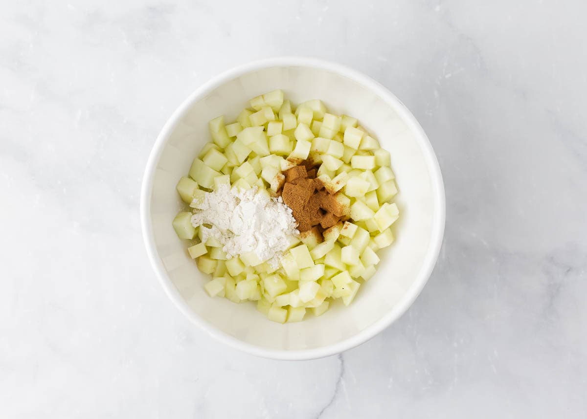 Diced apples in a bowl with spices and flour.