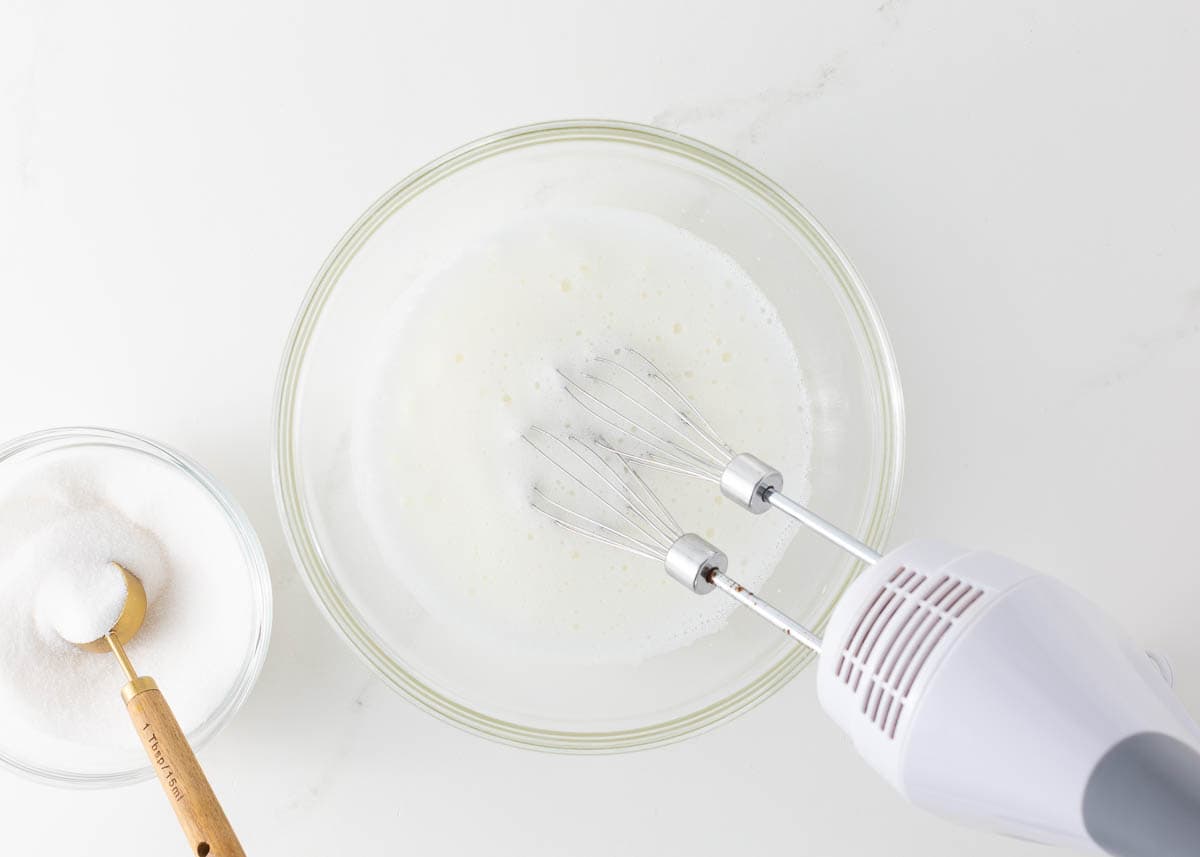 Showing beaten egg whites and adding sugar slow for meringue cookies.