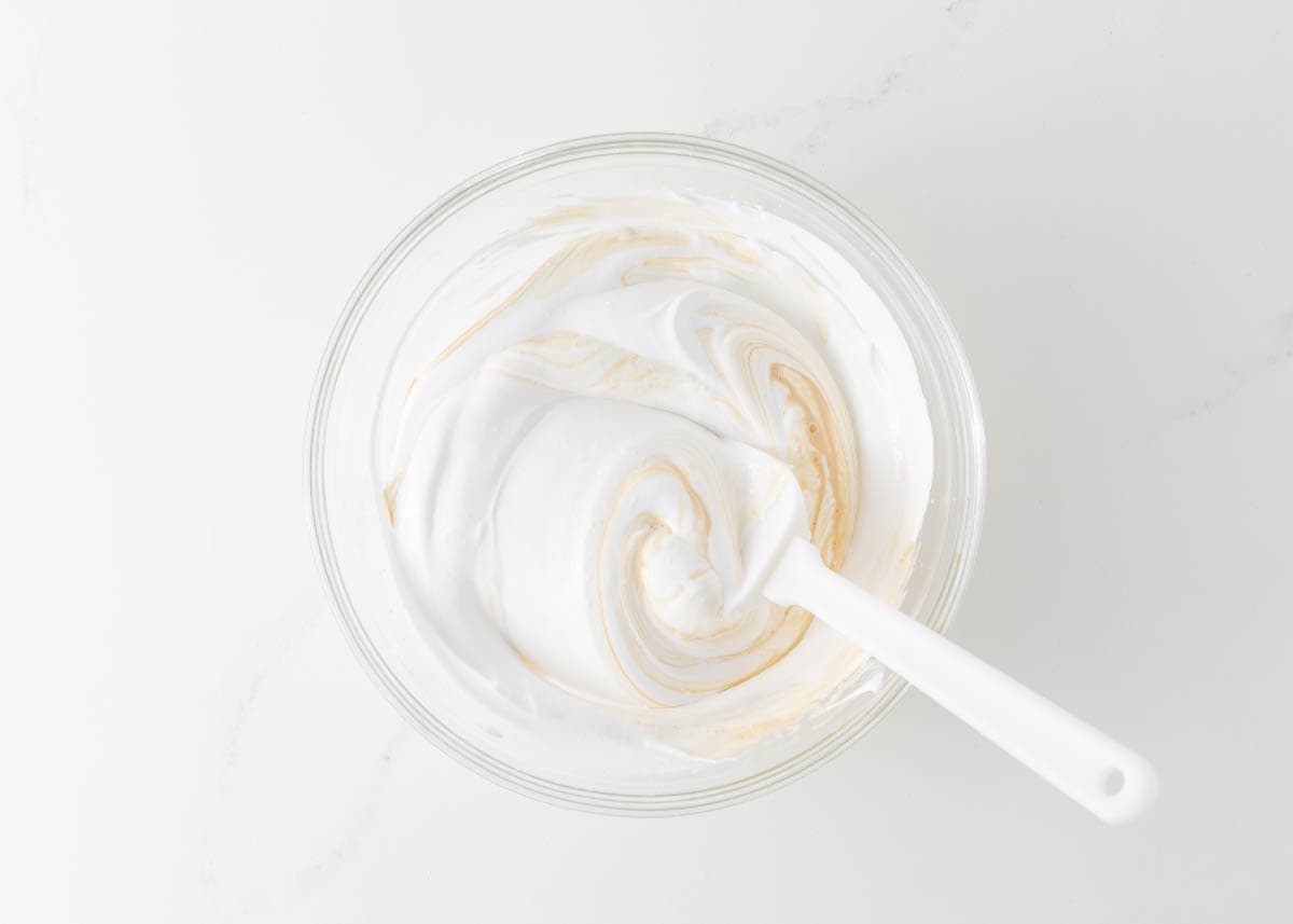 Adding vanilla to whipped meringue.