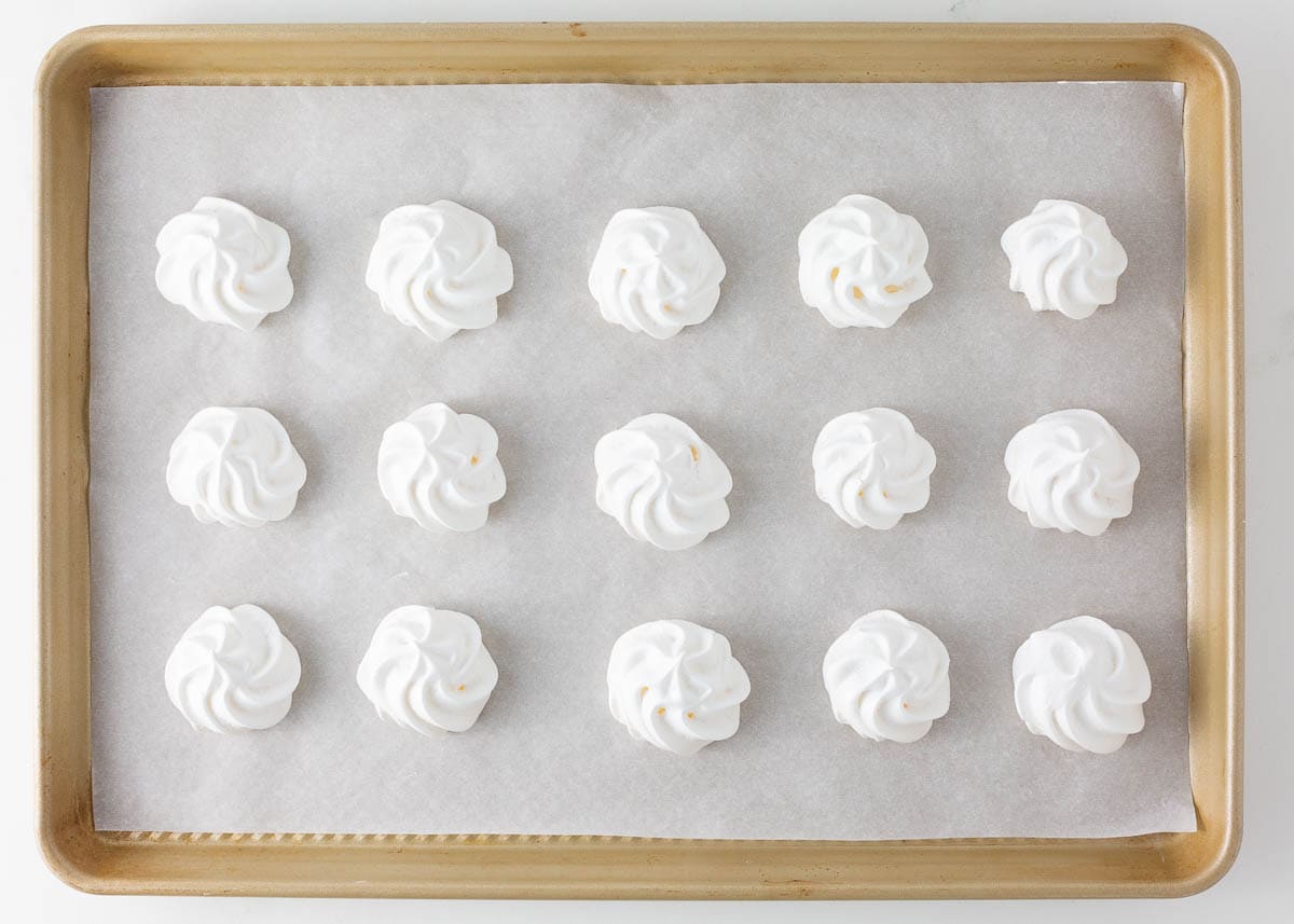 Baked meringue cookies on a baking sheet.