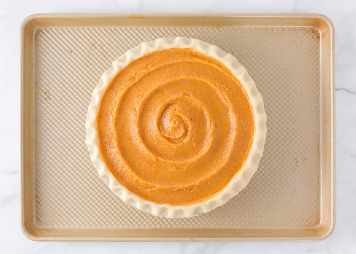 Unbaked sweet potato pie in a pie crust on a baking sheet.