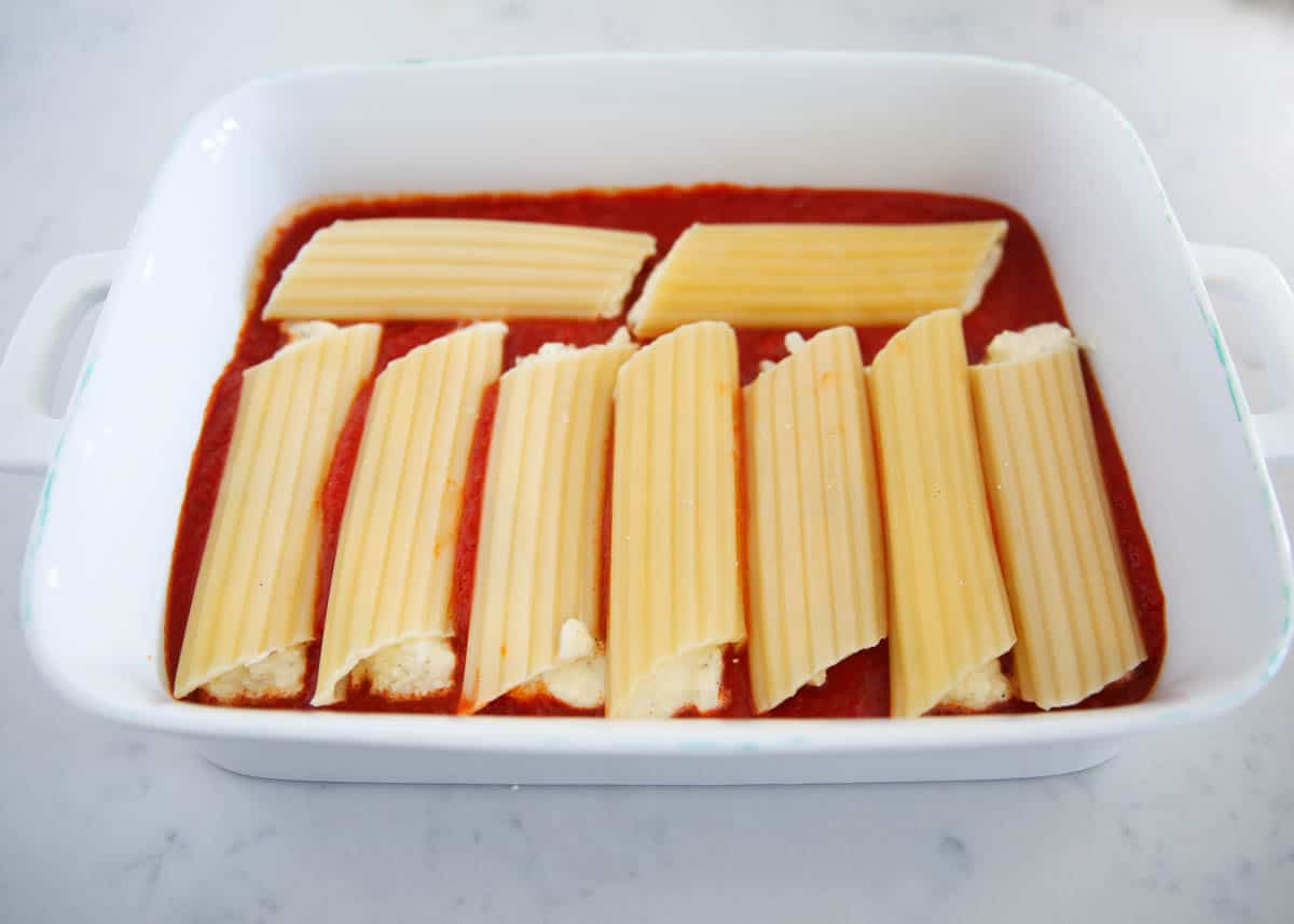 Stuffed three cheese manicotti noodles in baking dish.