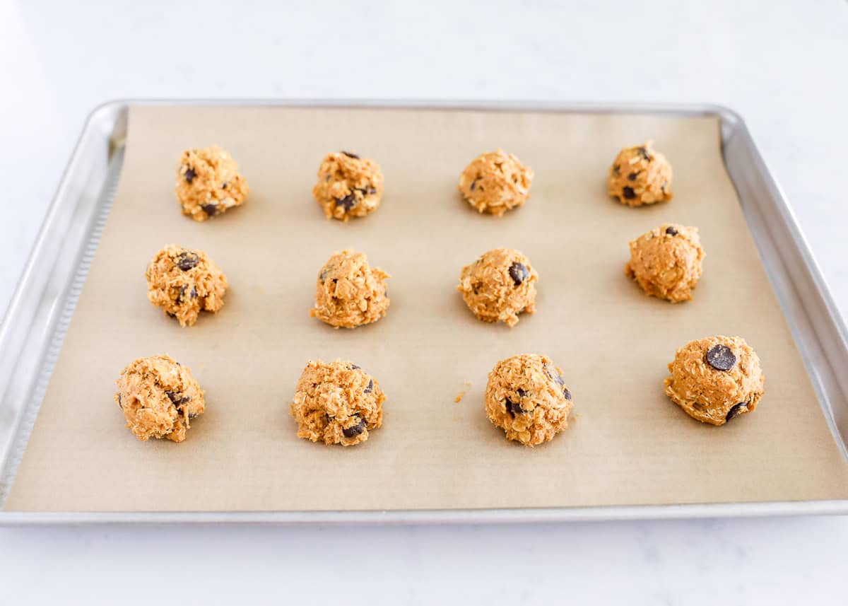 Pumpkin oatmeal chocolate chip cookie dough balls on a baking sheet.