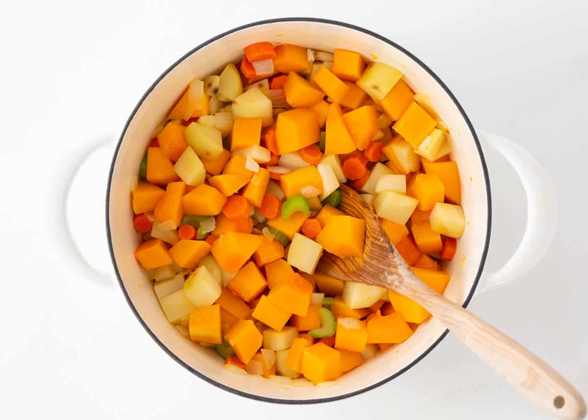 Veggies in a pot with a wooden spoon.