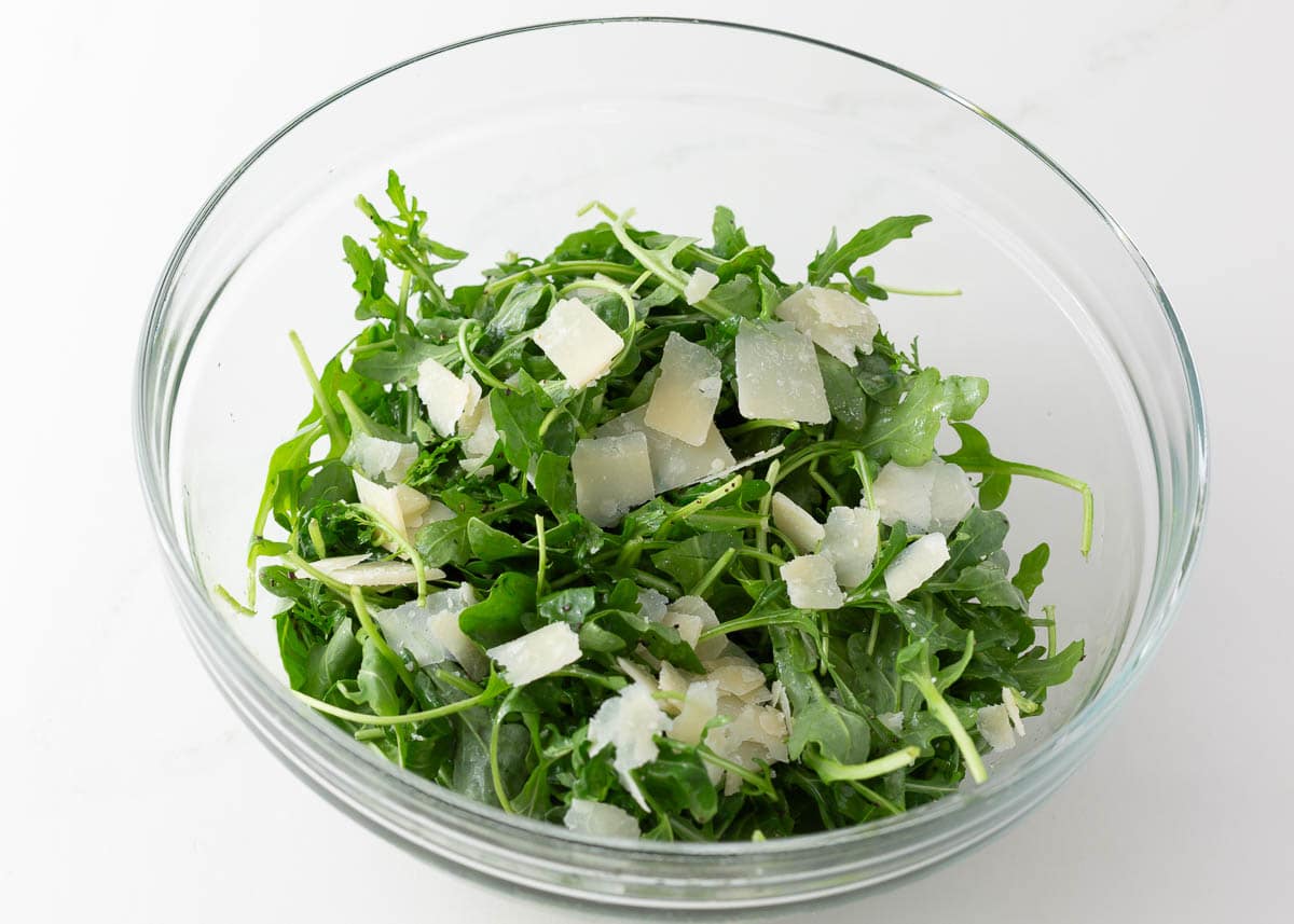 Arugula salad in a bowl to  pair with chicken Milanese.