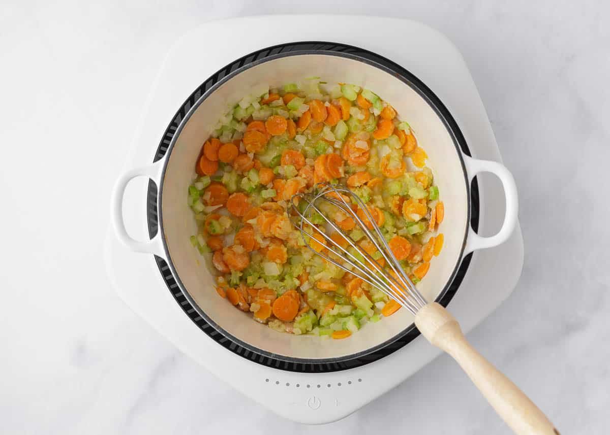 Sauteing carrots, onion and celery in butter in a large pot. 