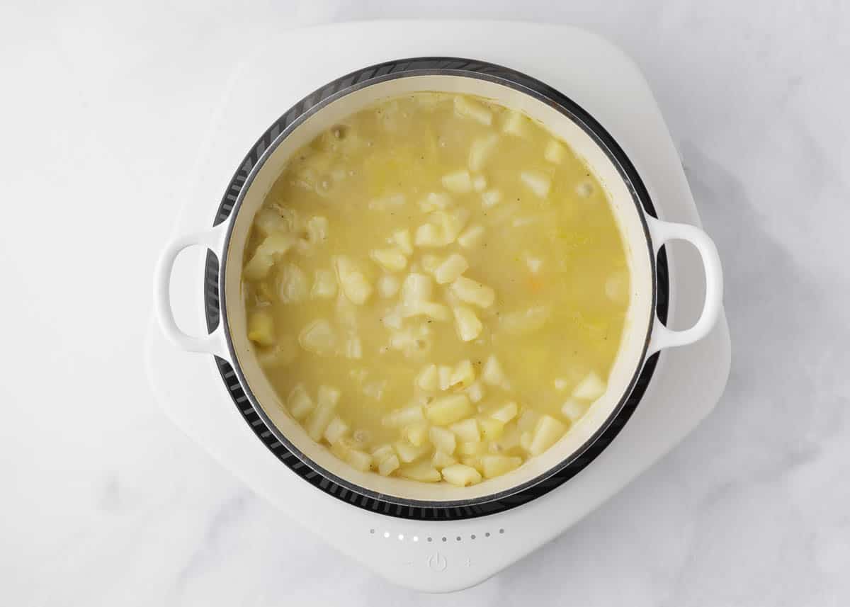 Ham and potato soup simmering in a pot.