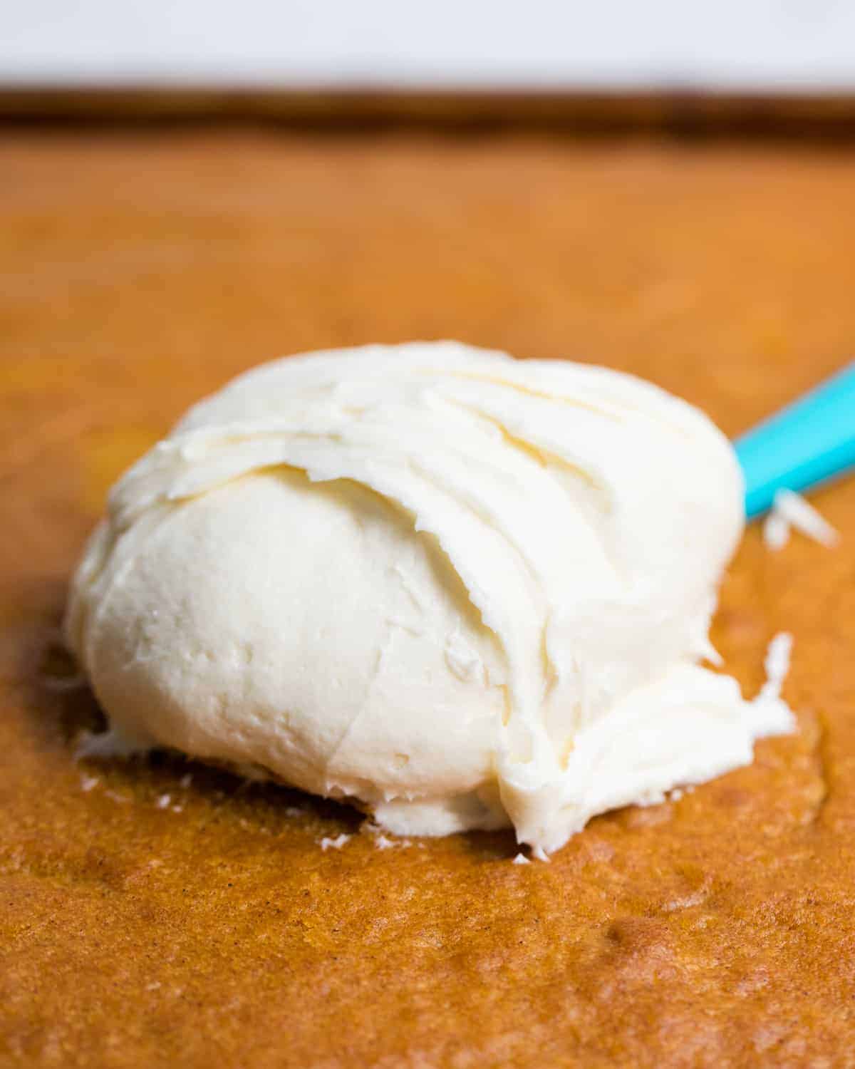 Cream cheese frosting being spread on pumpkin bars.