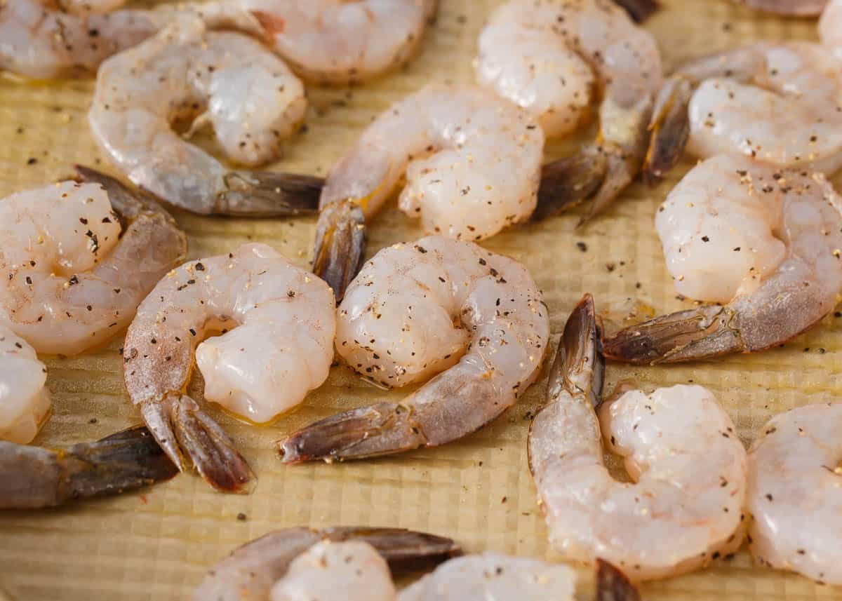 Unbaked shrimp on a baking sheet.