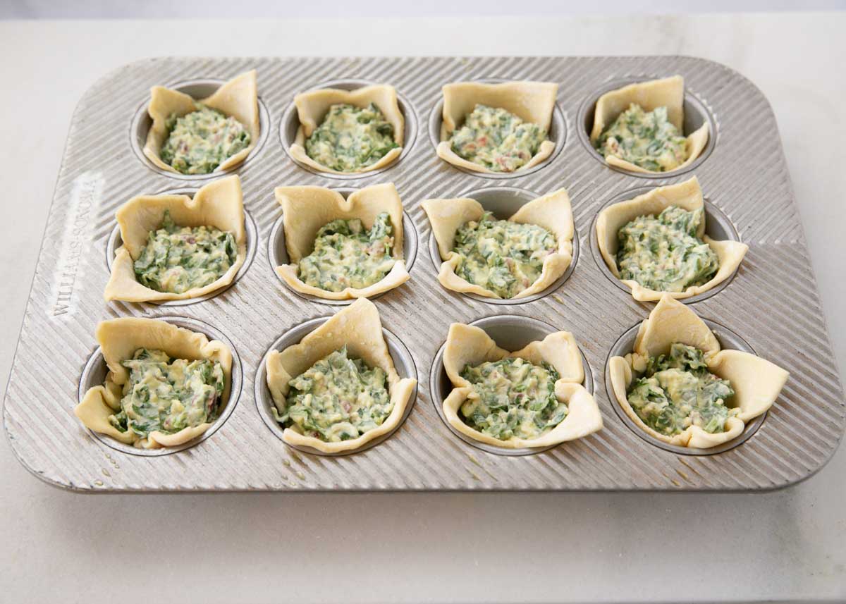 Puff pastry pressed into muffin pan and filled with spinach filling.