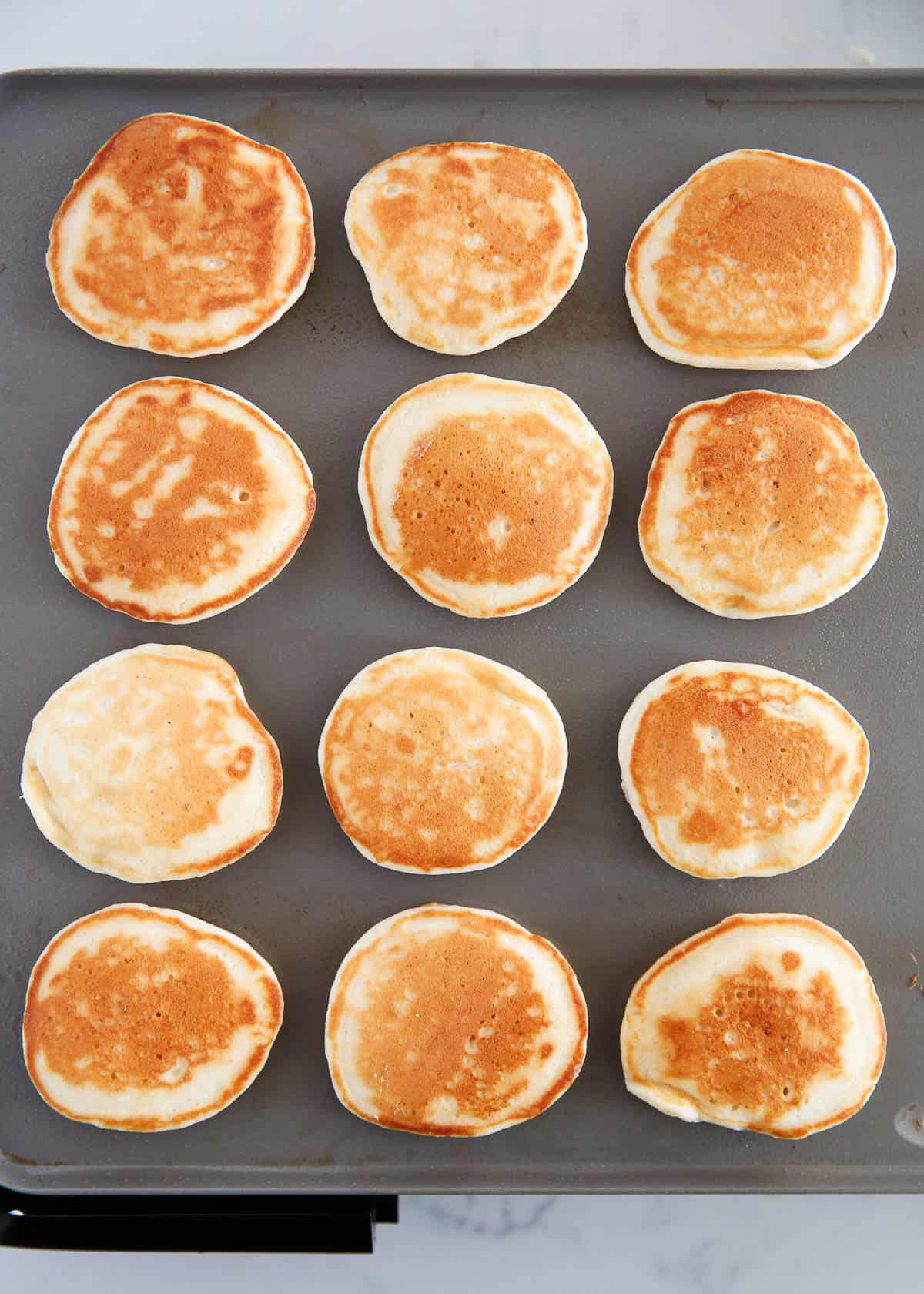 Silver dollar pancakes cooking on the griddle.