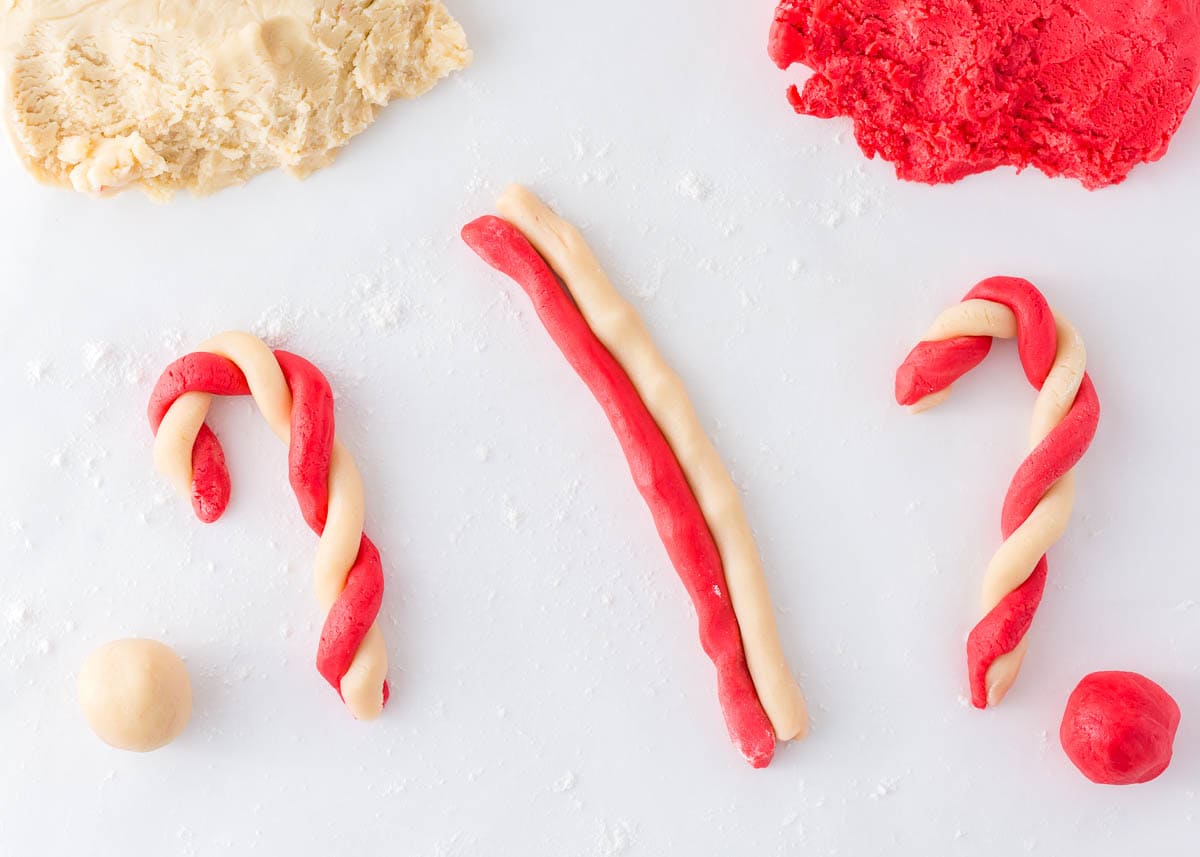 Twisting red and white cookie dough into candy cane shapes.