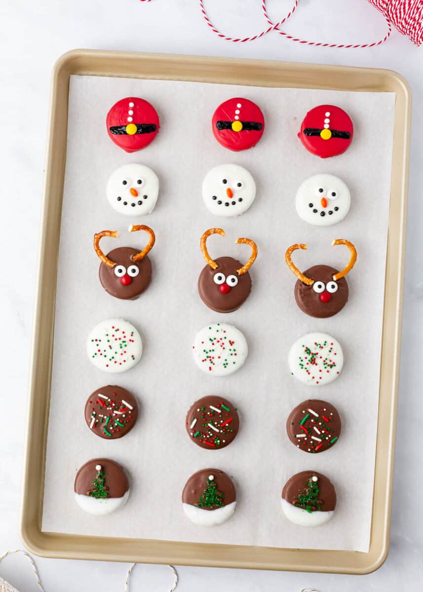 A baking tray of decorated Christmas Oreo cookies.