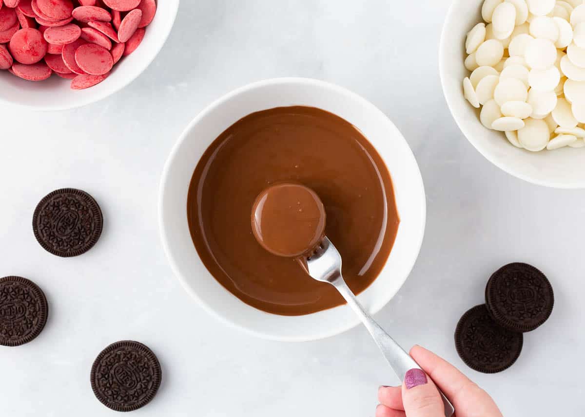 Dipping an Oreo into chocolate for Christmas Oreos.