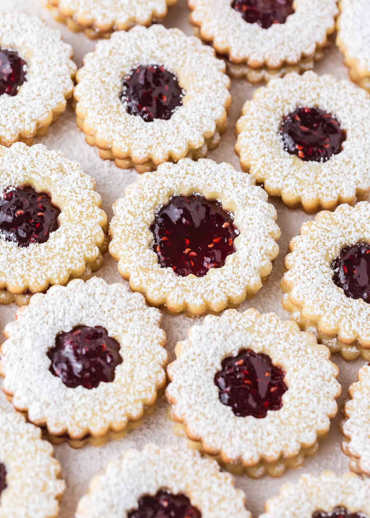 Linzer cookies filled with raspberry jam on the counter.