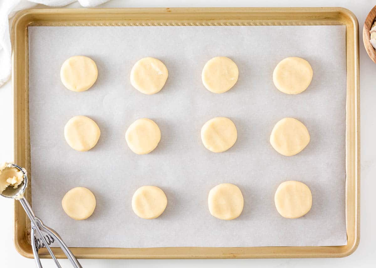 Unbaked almond cookies on a parchment lined baking sheet.