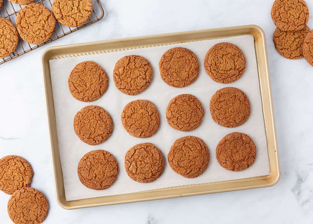 Crisp gingersnap cookies on a parchment lined baking pan.