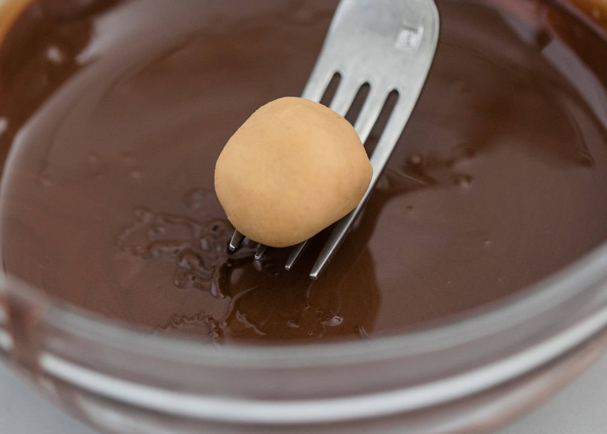 Dipping peanut butter balls into chocolate.