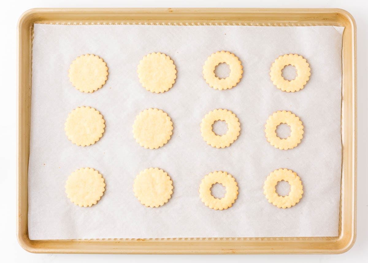 Linzer cookies on a parchment lined baking pan.