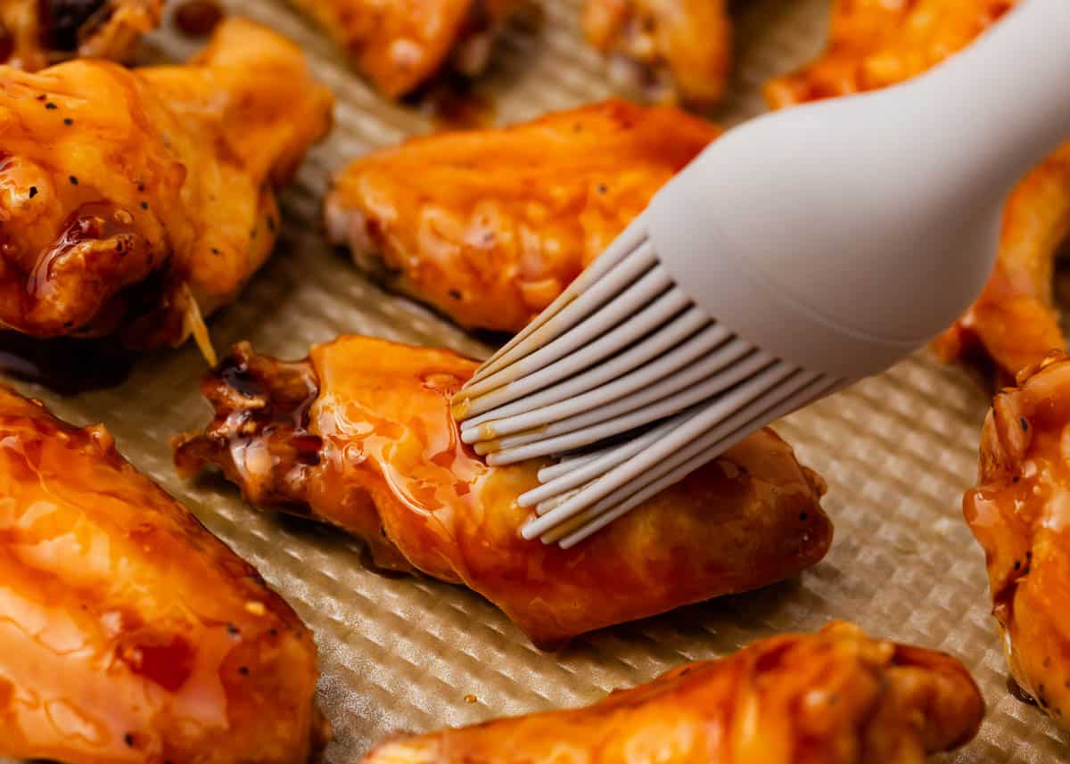 Adding sauce to baked chicken wings recipe.