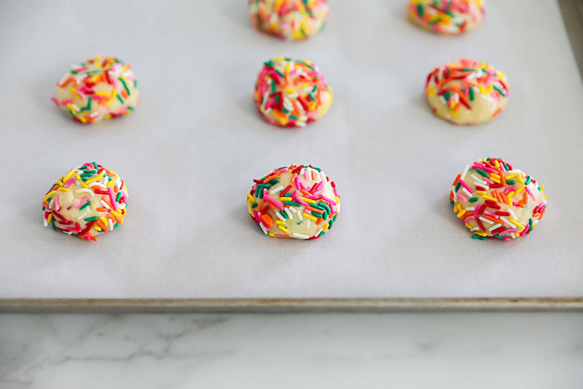 Funfetti cake mix cookies on parchment paper lined baking sheet.