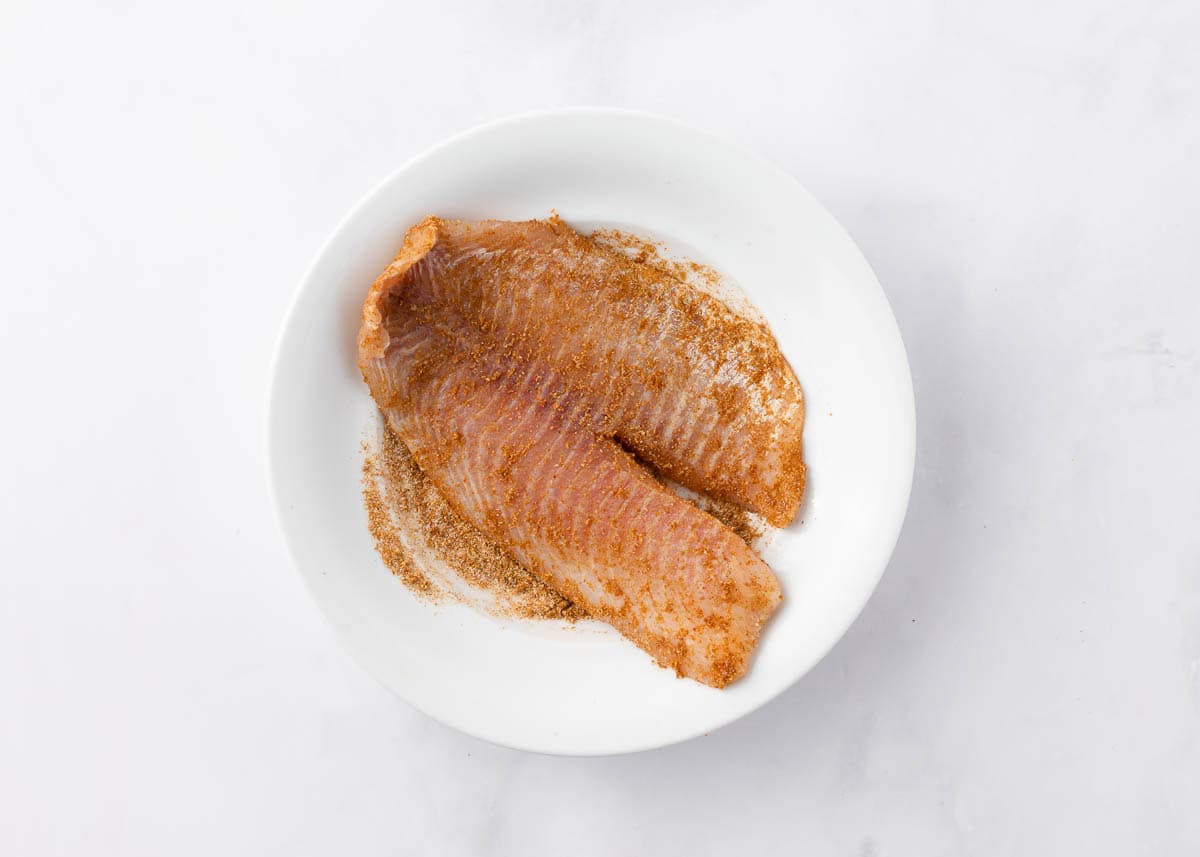 Seasoning tilapia fillets. 